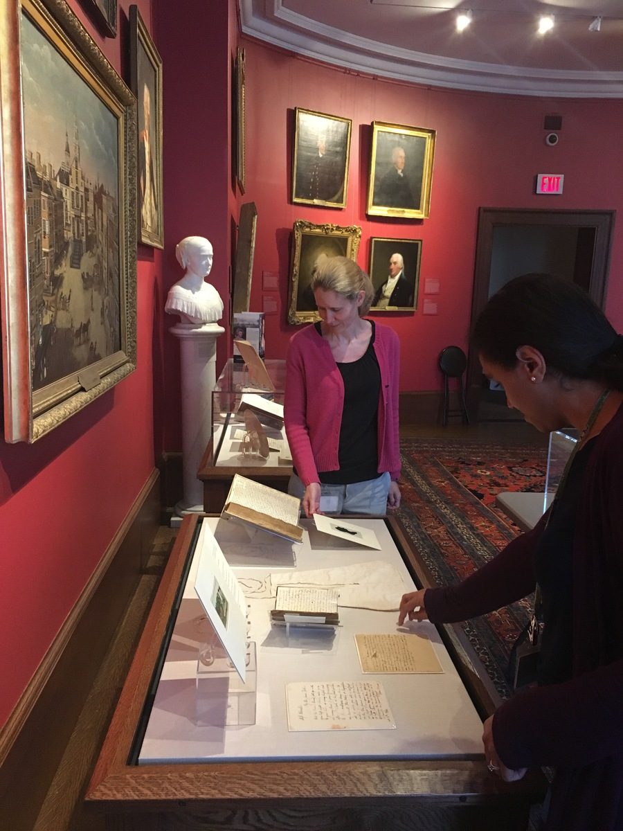 Two women placing objects in exhibit case